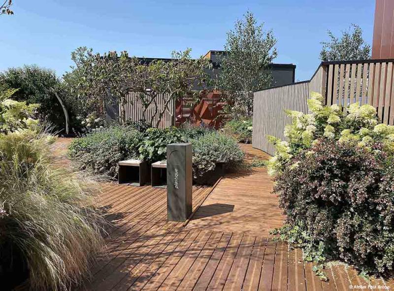 A wooden terrace greeted by generous plant masses that draw a living and enveloping landscape